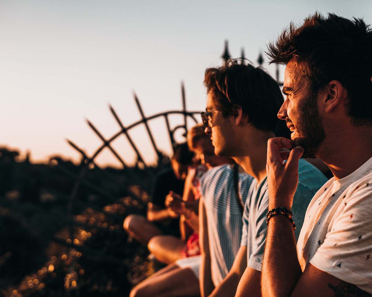 person man sitting on fence facing right way under golden hour human