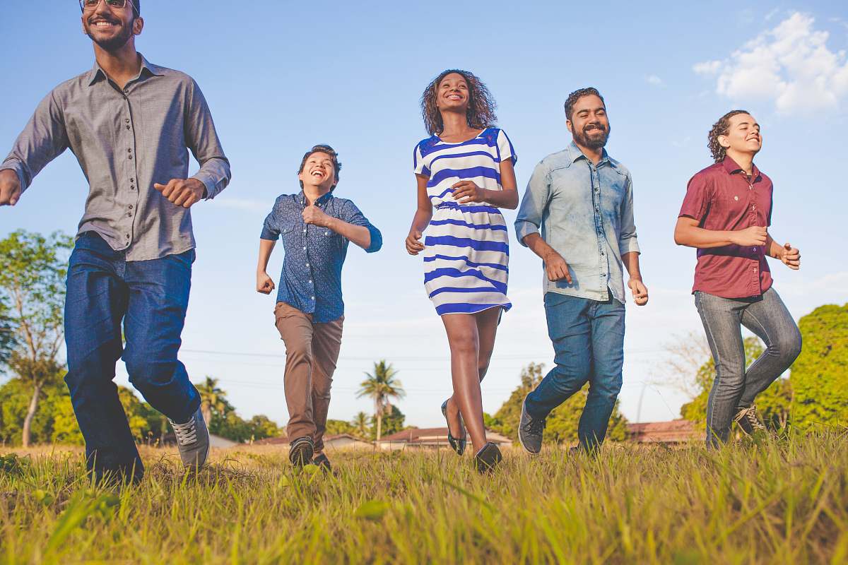 human people running on grassfield under blue skies at daytime person