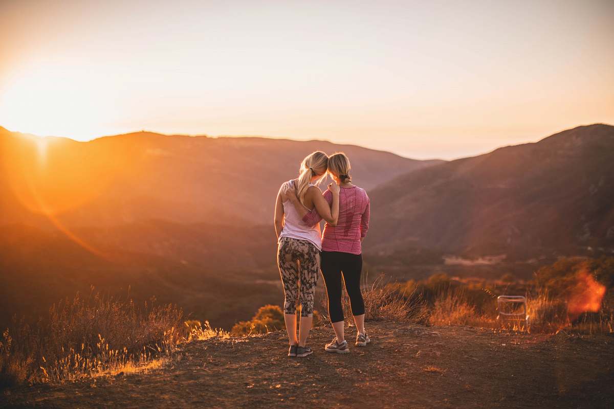 Capture the essence of adventure and connection with this breathtaking image of two women standing together on a mountain peak at sunset. The warm hues of the setting sun create a magical atmosphere, making it an ideal visual for travel blogs, motivational content, or campaigns celebrating friendship and empowerment. This captivating scene not only showcases natural beauty but also evokes feelings of freedom and exhilaration.