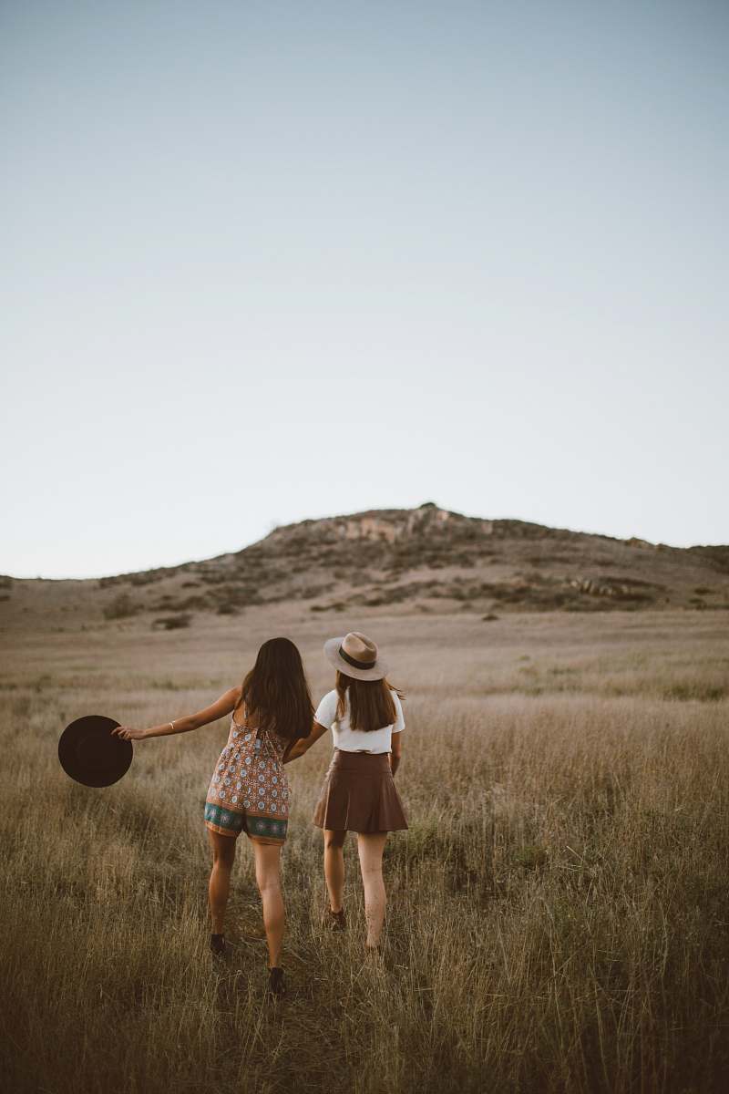 woman two women walking around near mountain at daytime field