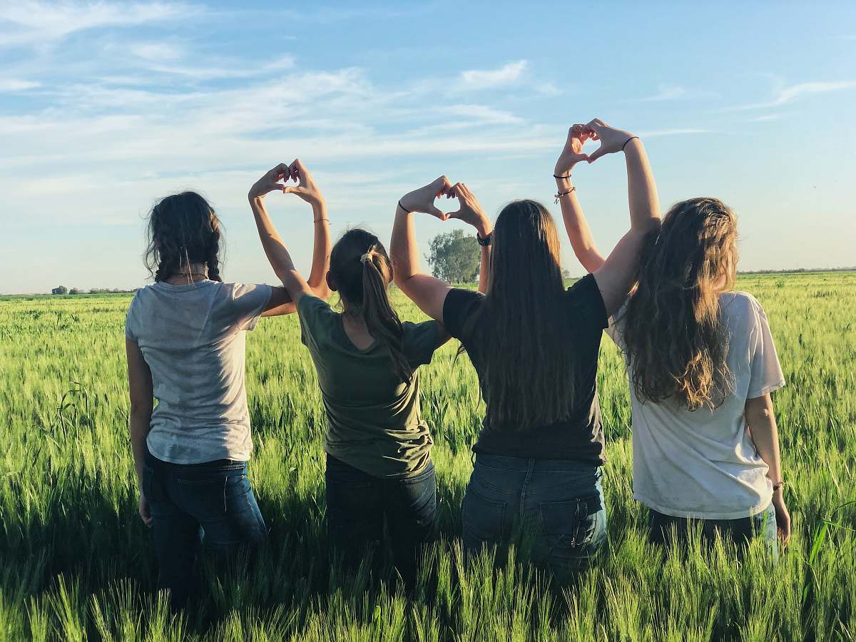 human women forming heart gestures during daytime person