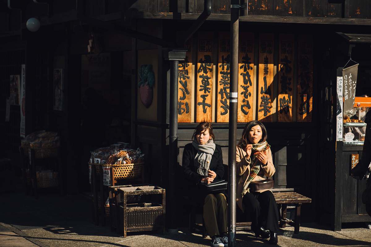 people two women sitting on bench outdoor during daytime human