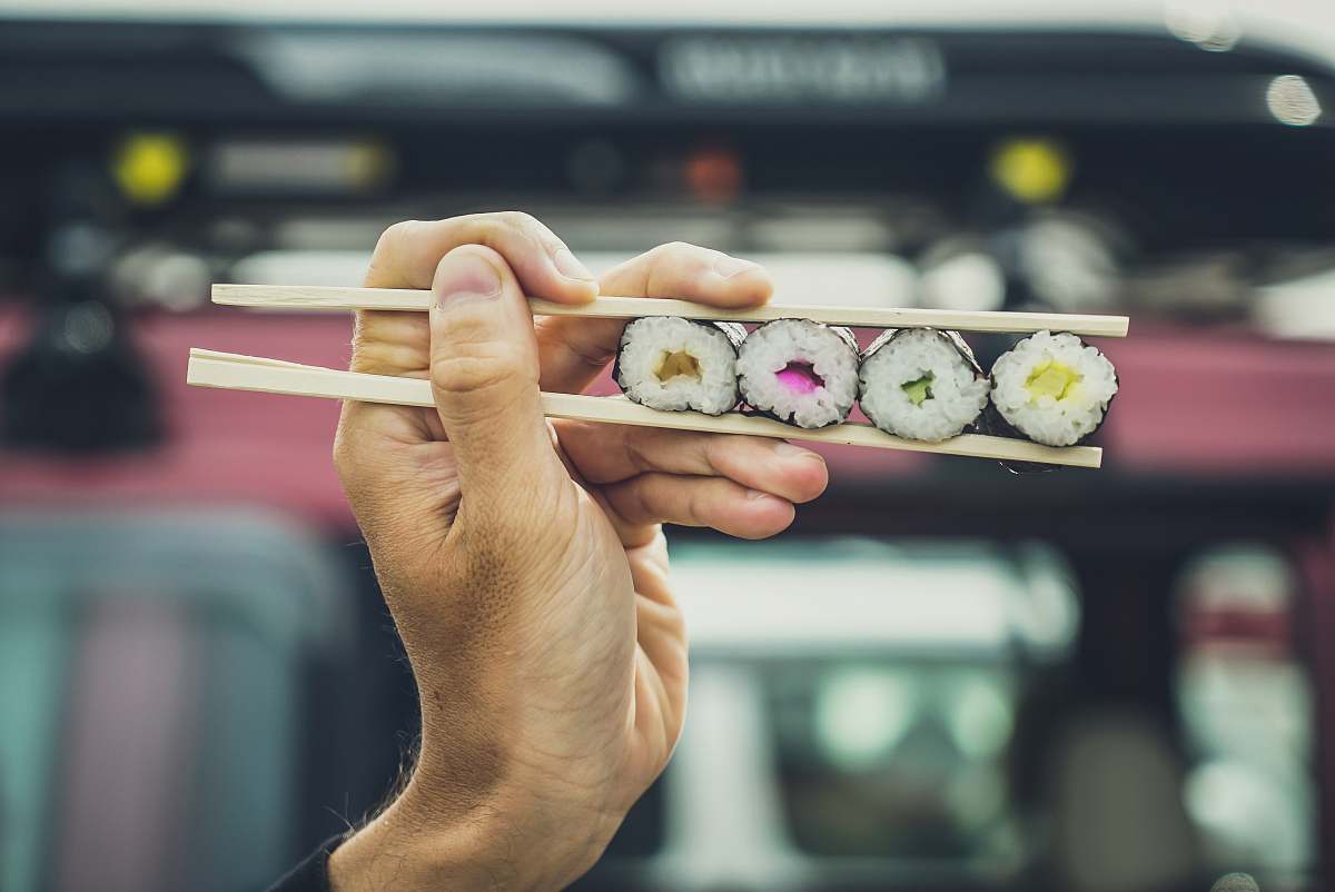 human cooked sushi on chopsticks finger