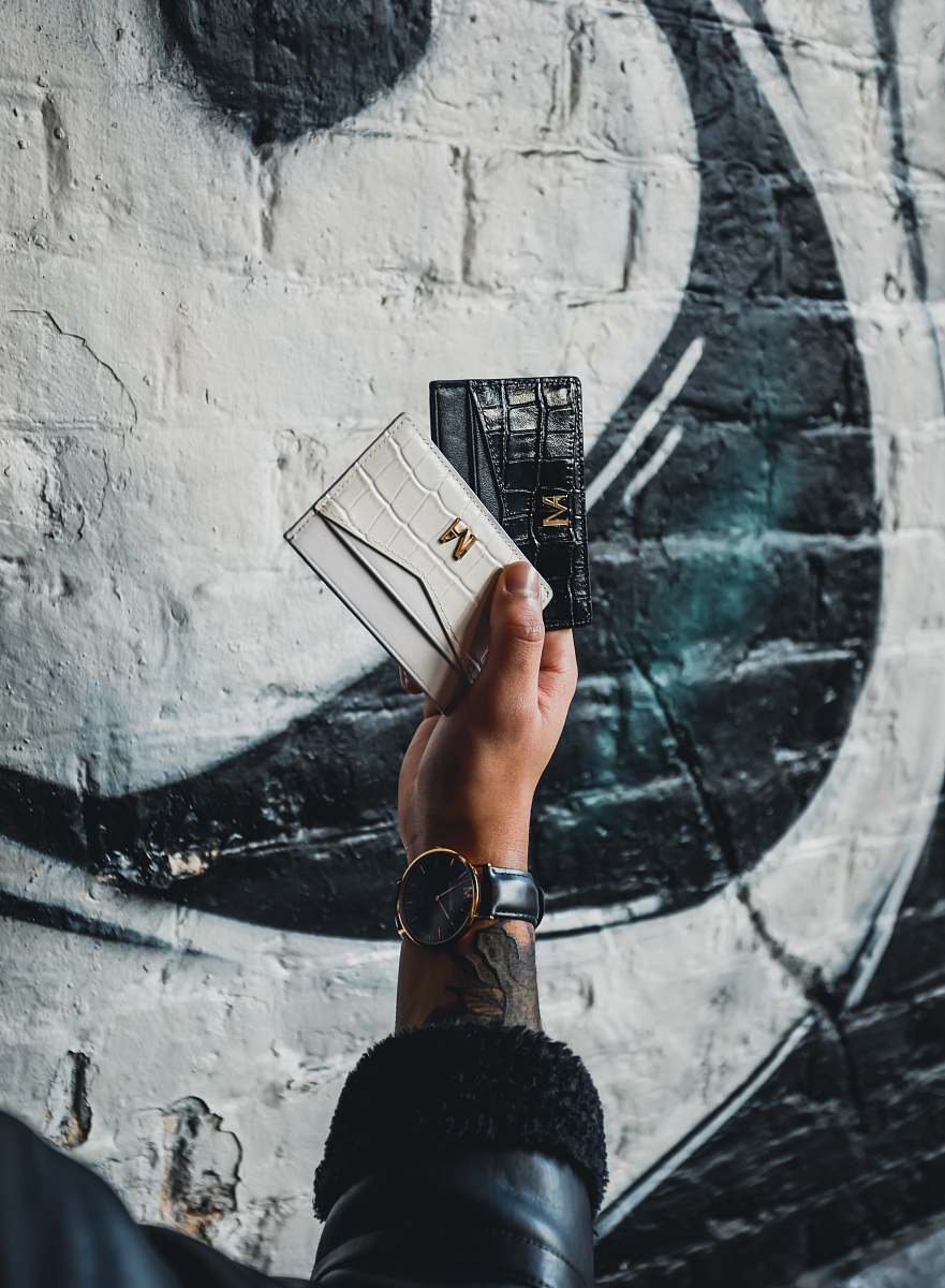 human person holding black and white leather wallets finger