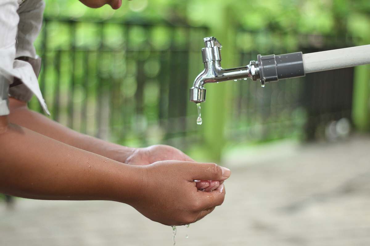 human person washing hands in open faucet indoors