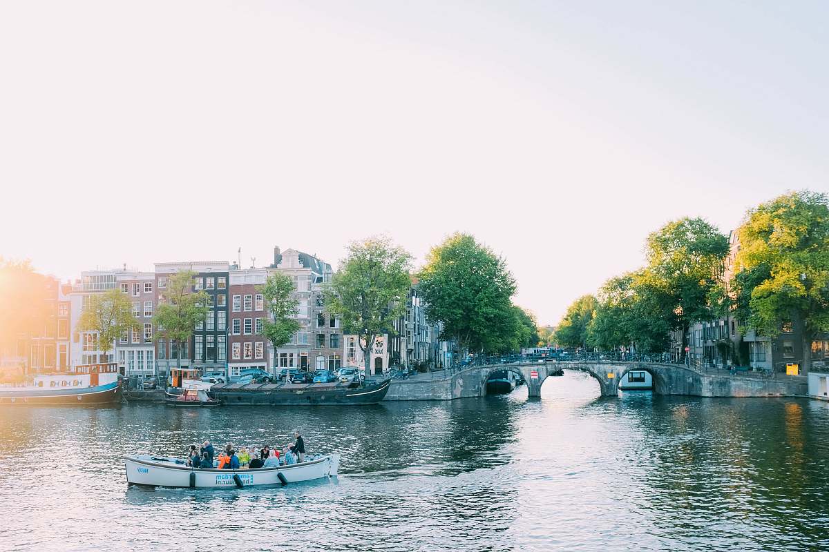 outdoors people riding canoe beside concrete bridge at daytime canal