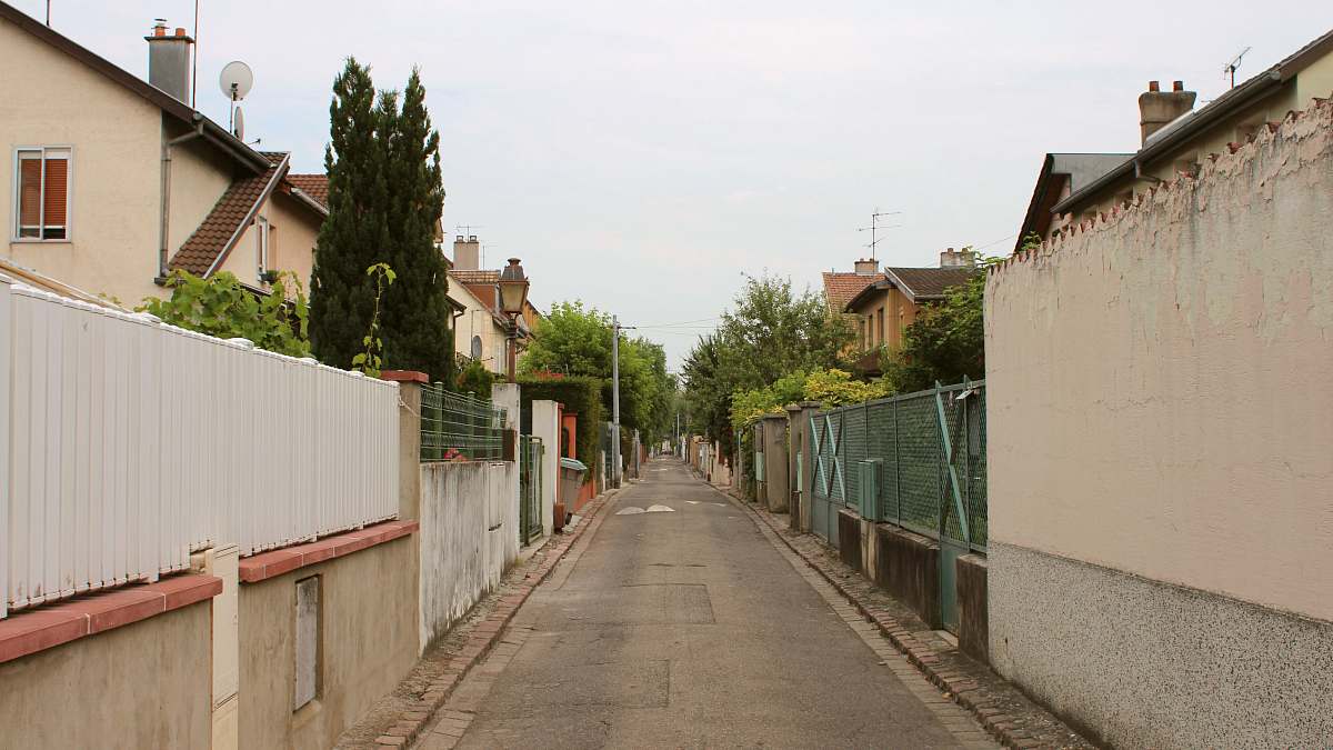 perspective gray concrete walkway surrounded by houses during daytime town