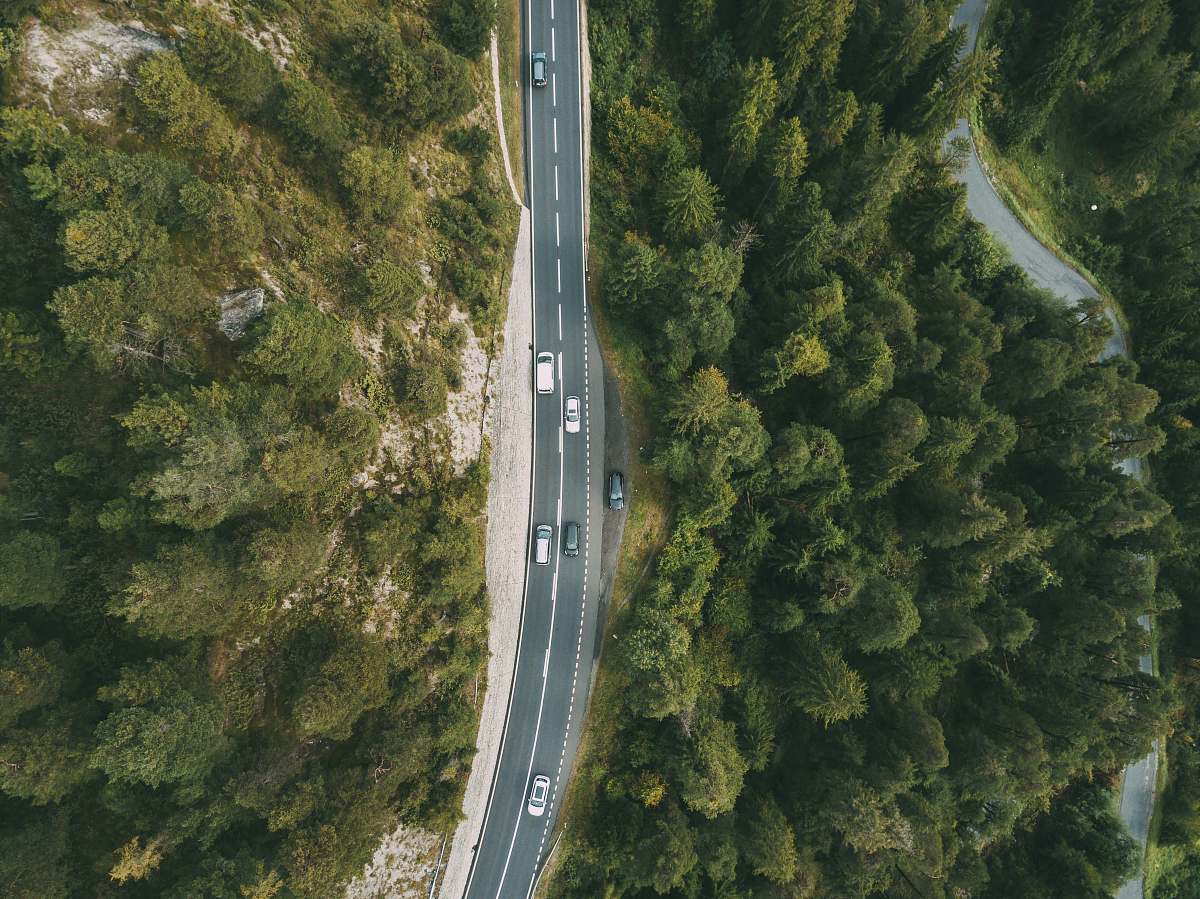 road aerial photography of vehicle passing by highway between green trees switzerland