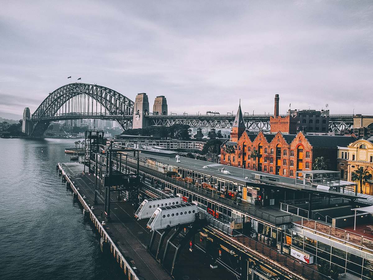 australia aerial photography of concrete buildings and bridge beside ocean under cloudy sky sydney