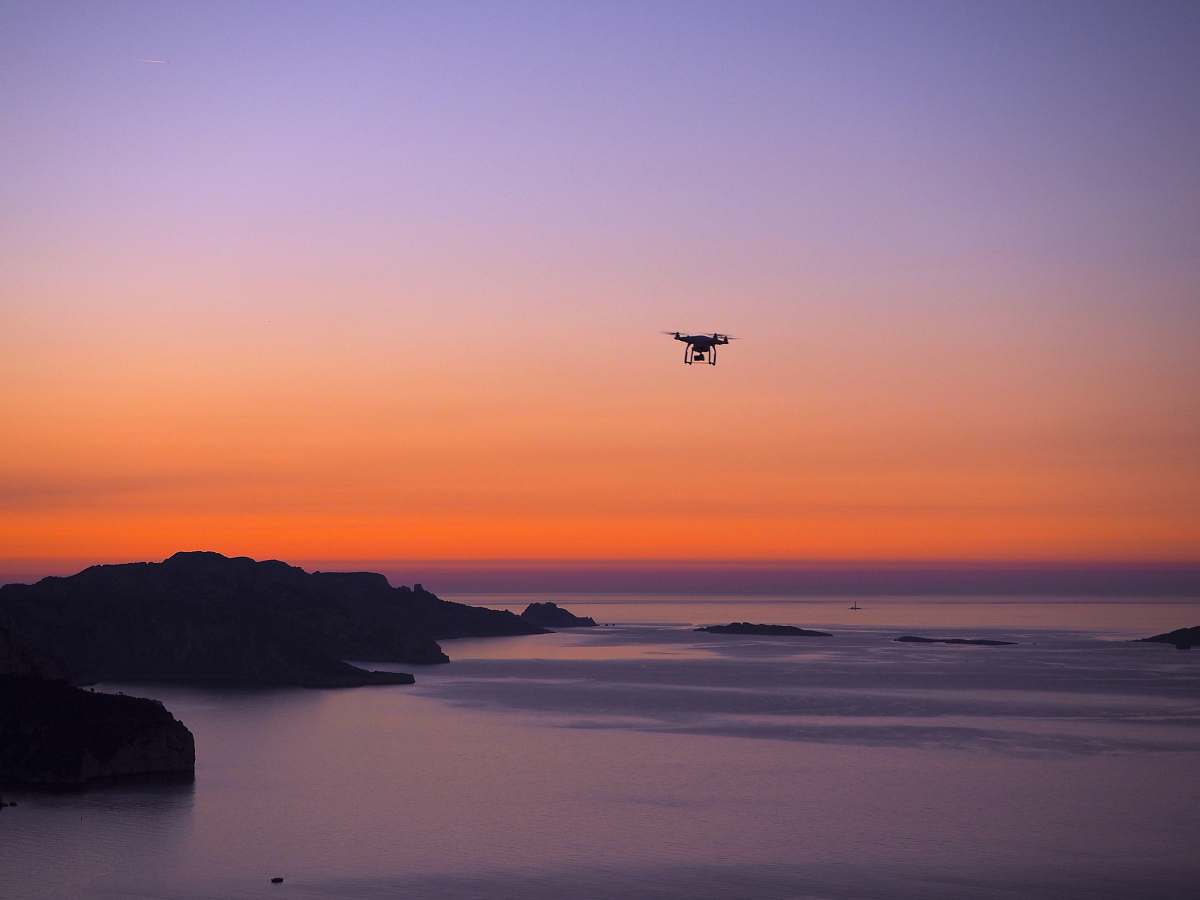 dawn silhouette photo of drone on seashore sunset