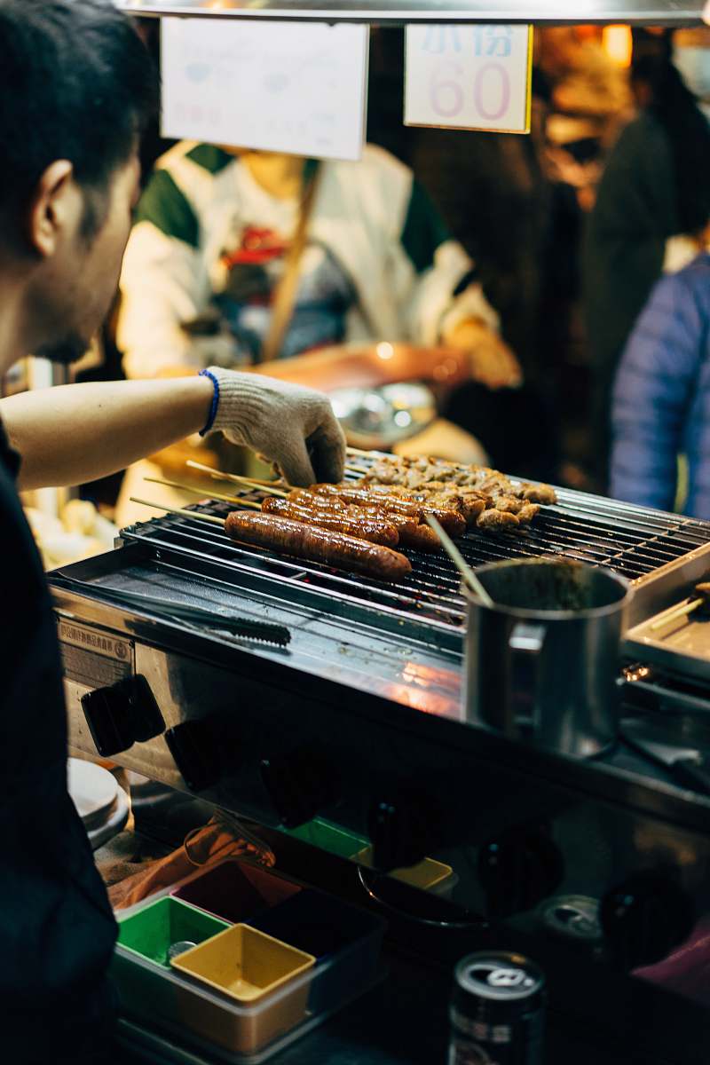 person man barbecuing skewered sausages human