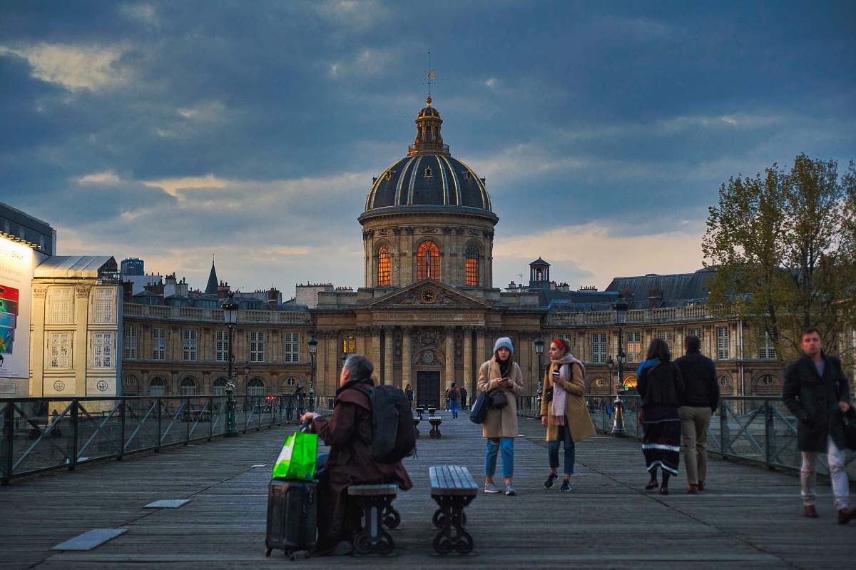 person people walking and sitting in front of brown concrete dome building during golden hour pedestrian