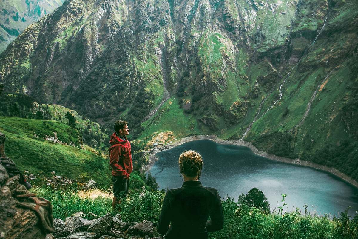 outdoors woman and man standing on mountain near creek during daytime mountain
