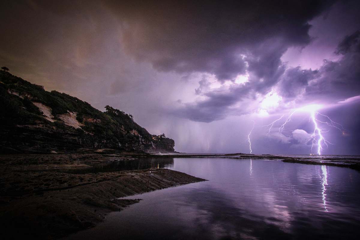 thunderstorm lightning near body of water and rock formation nature