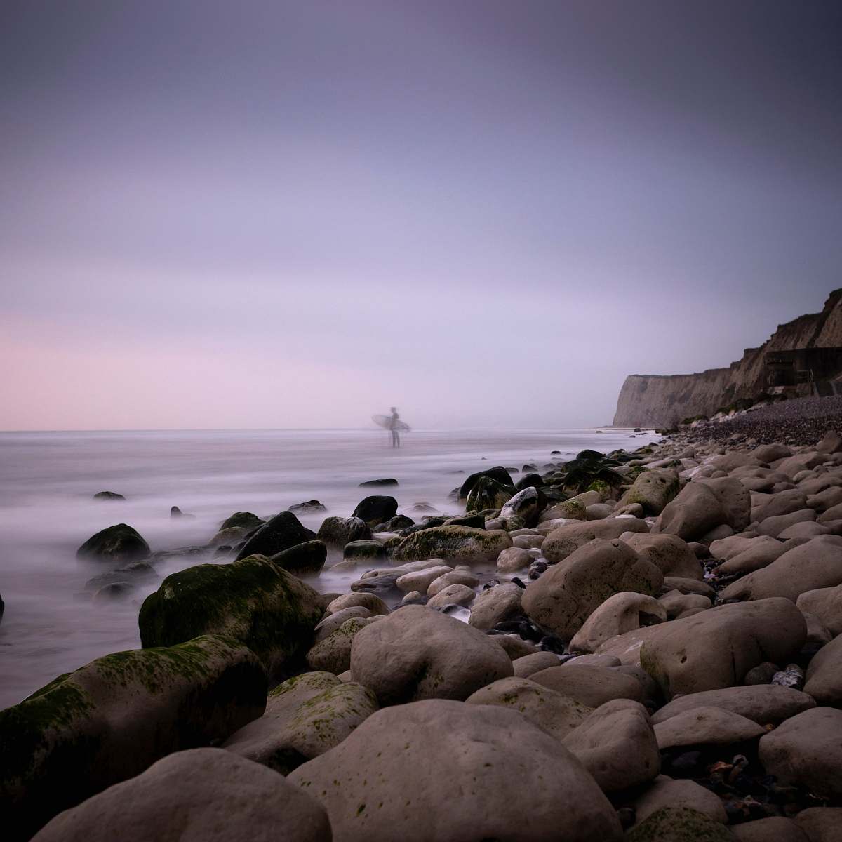 rock surfer standing on seashore ocean