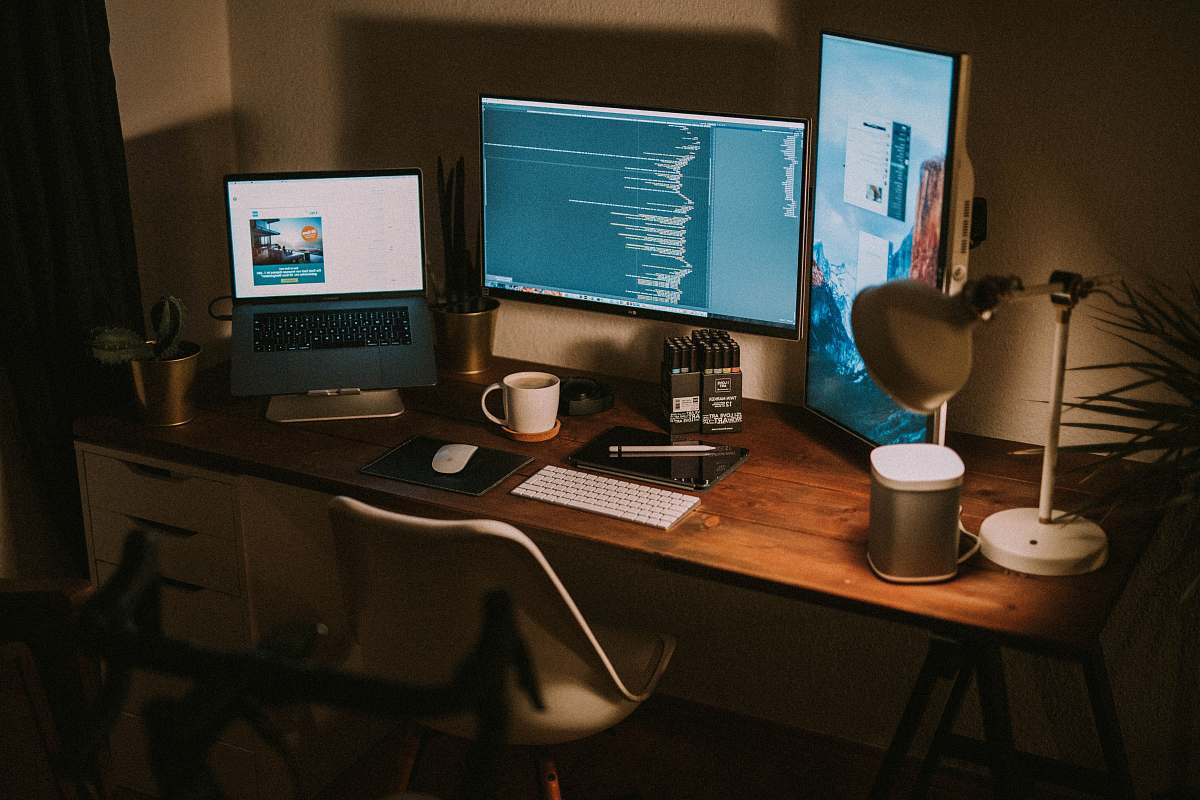 table turned on flat screen monitors and MacBook Pro furniture