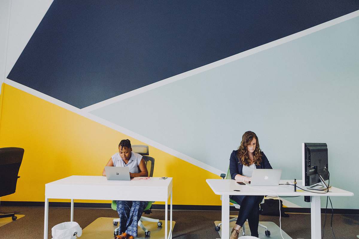 table two women sitting beside table using MacBooks furniture