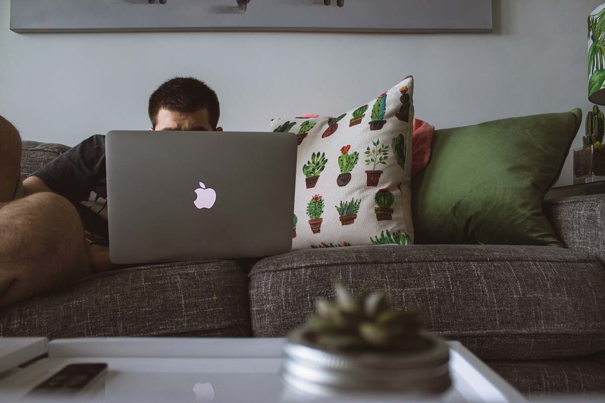 couch man using MacBook sat on sofa man working