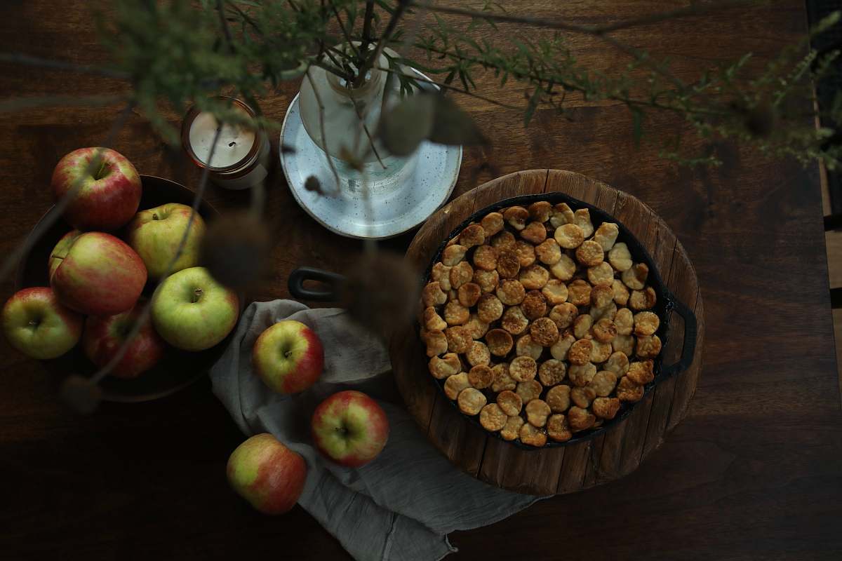 apple brown round food on brown wooden round bowl beside green apple fruit on brown wooden table fruit