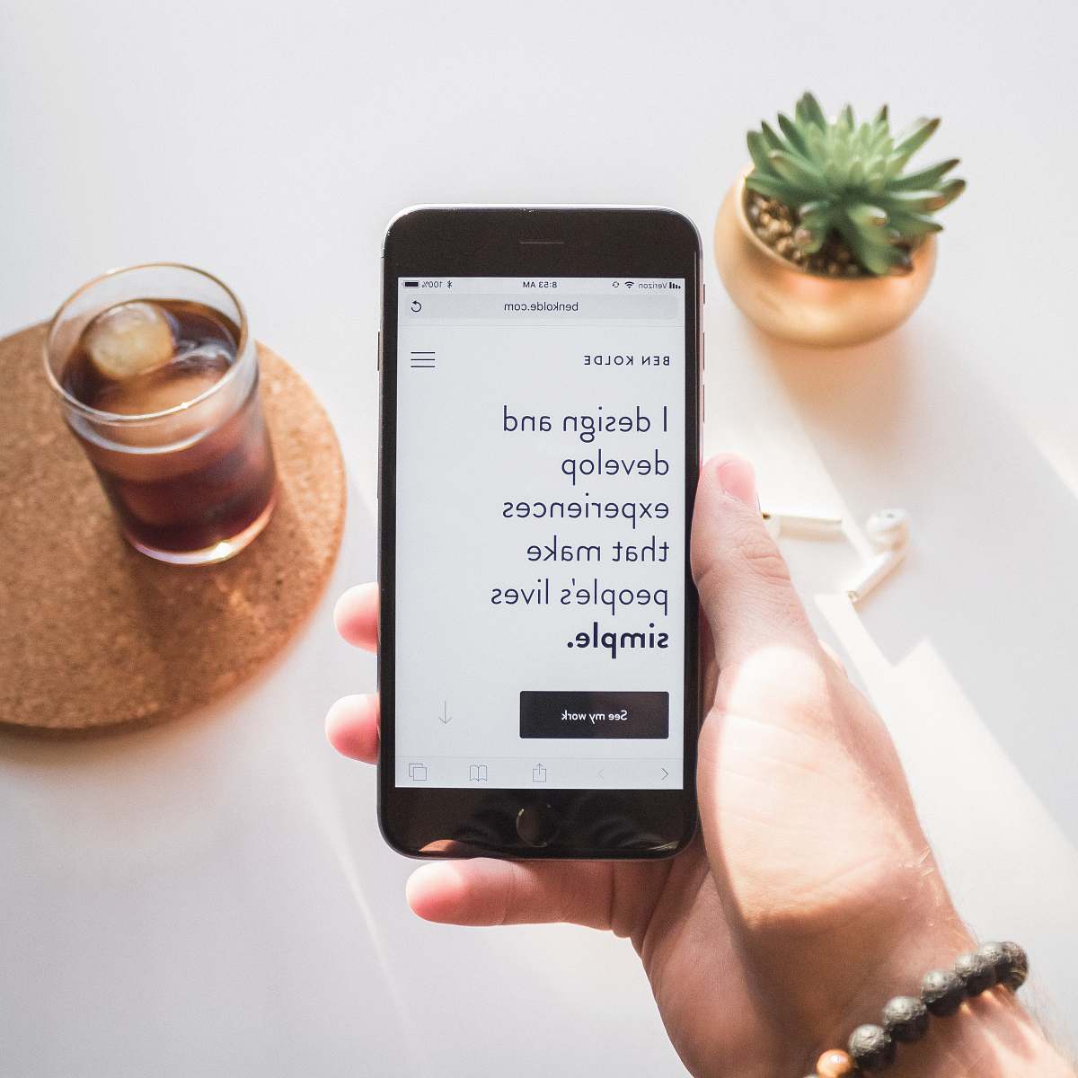 beverage person holding space gray iPhone 6 displaying i design and develop experiences that make people's lives simple text phone