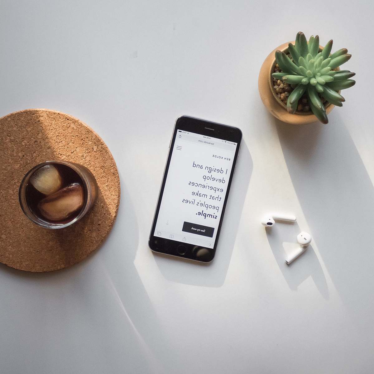 phone post-2014 iPhone beside Apple AirPods and succulent plant on white surface website