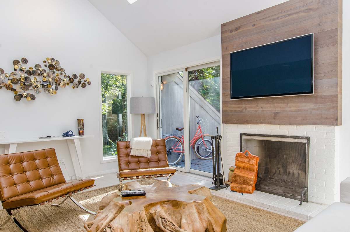 furniture two tufted brown leather chairs in front of brown wood stump center table fireplace