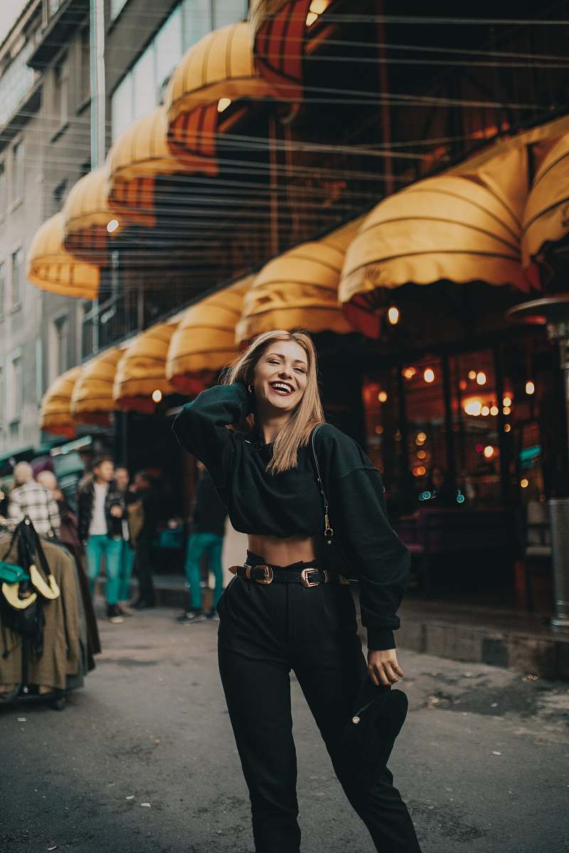 apparel woman wearing black crew-neck sweater with shoulder bag standing on road near buildings during daytime clothing