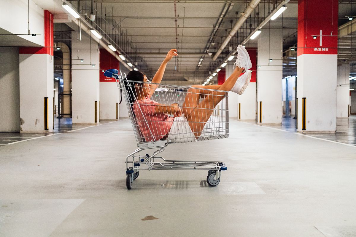 woman sitting in shopping cart at parking lot