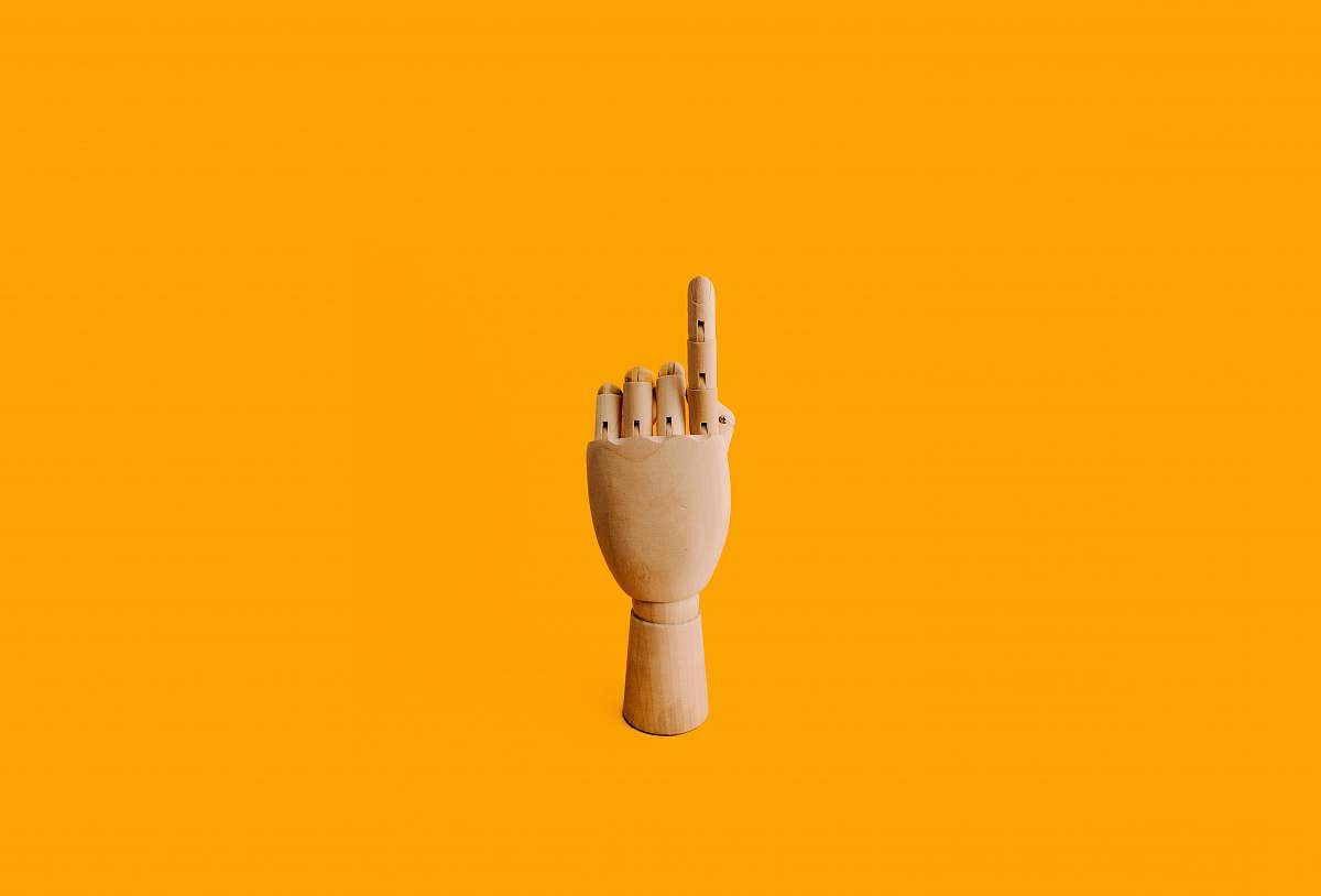 yellow beige wooden hand sculpture with orange background manikin