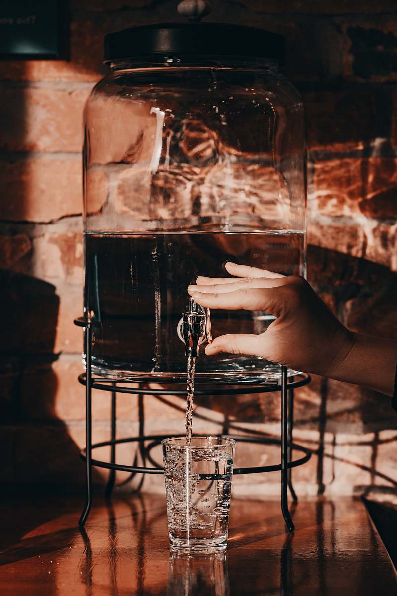 human person pouring water on glass from jug person
