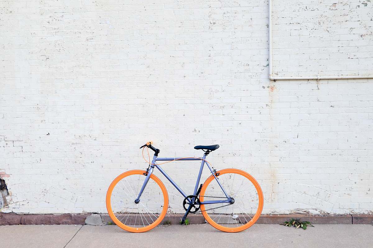 bicycle yellow and purple bicycle near white wall at daytime bike