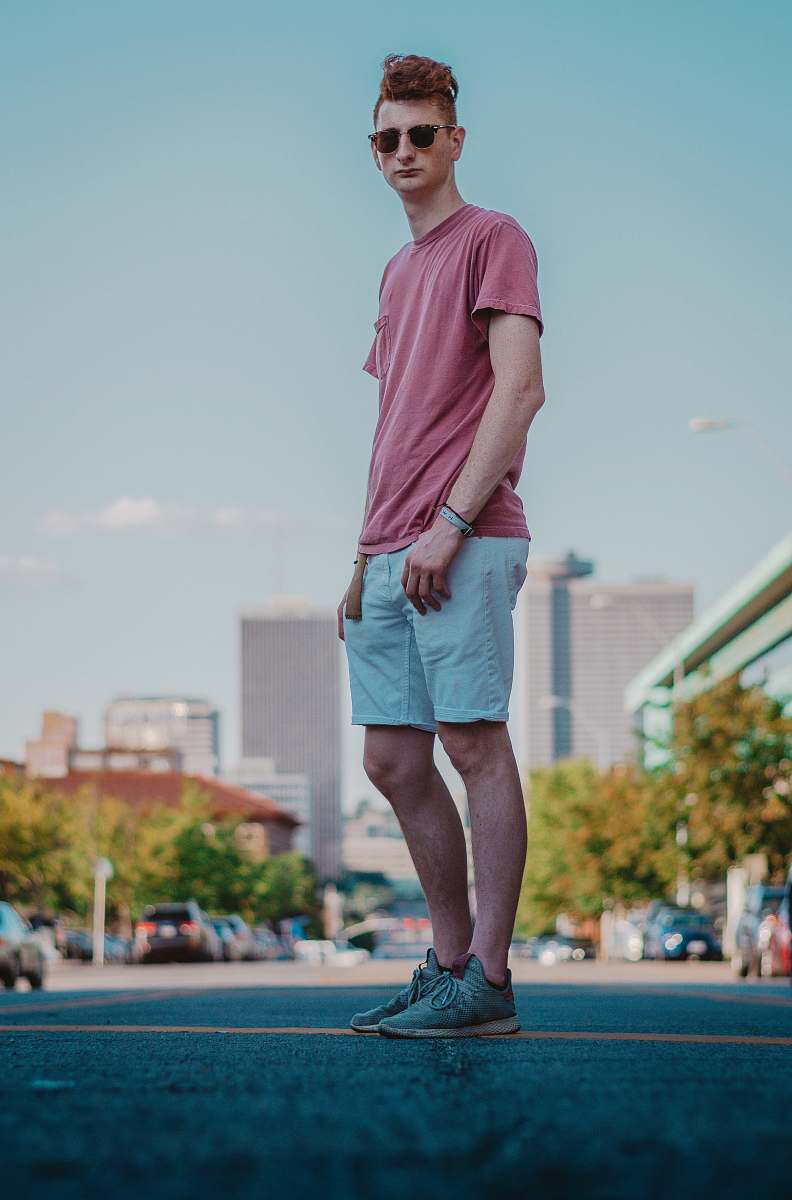 clothing man in red t-shirt and gray shorts standing on field during daytime shorts