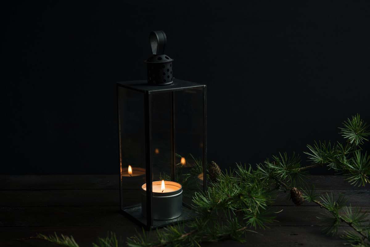 flora lighted candle inside black lantern holder jar