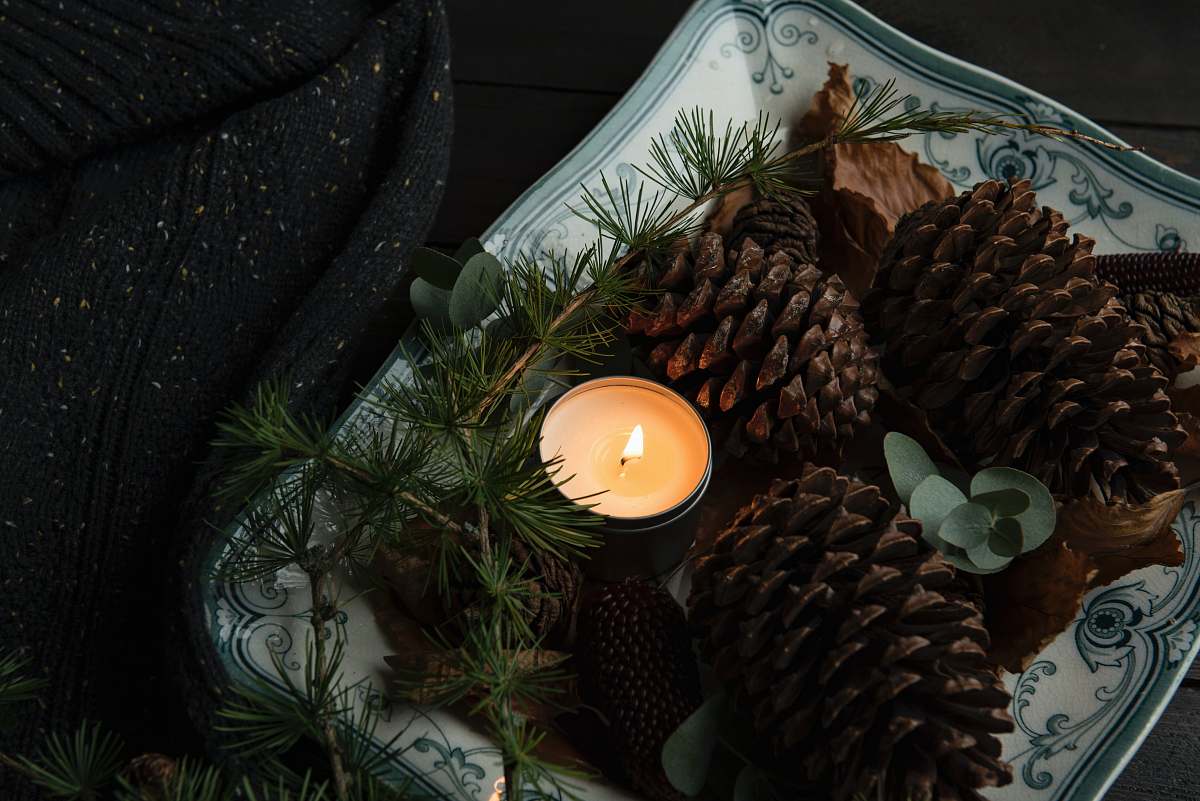 candle lighted candle on plate beside the pinecones autumn