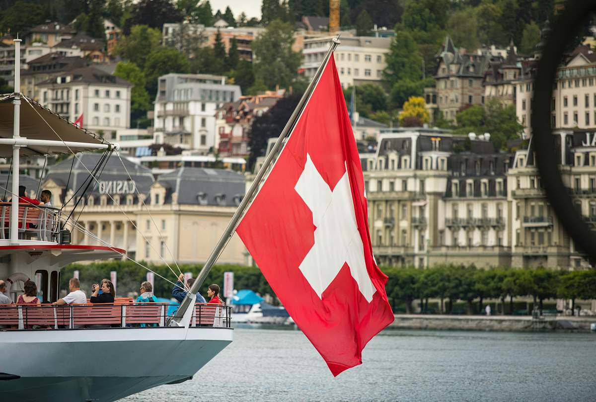 symbol red and white sail boat on water near city buildings during daytime human