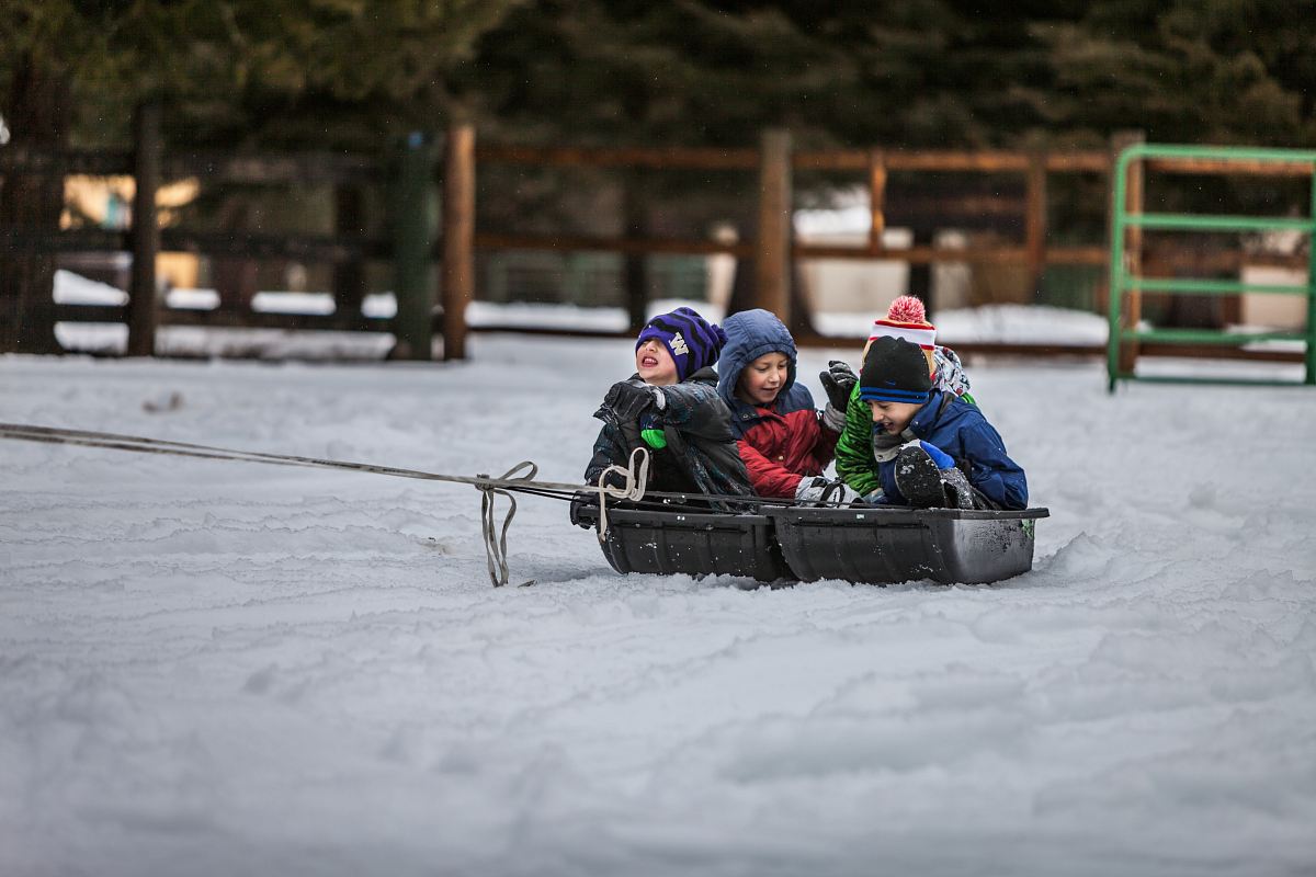 four children riding boat on snow