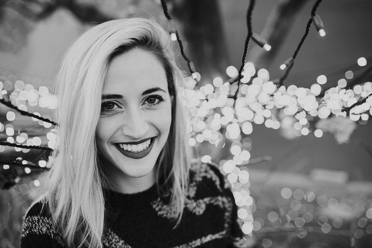 grayscale photo of woman with string lights