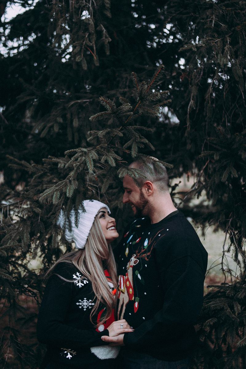 man and woman looking each other standing under green leafed tree