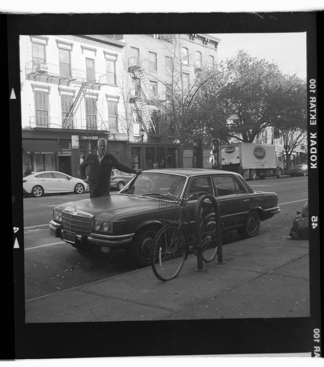 man standing on parked black car