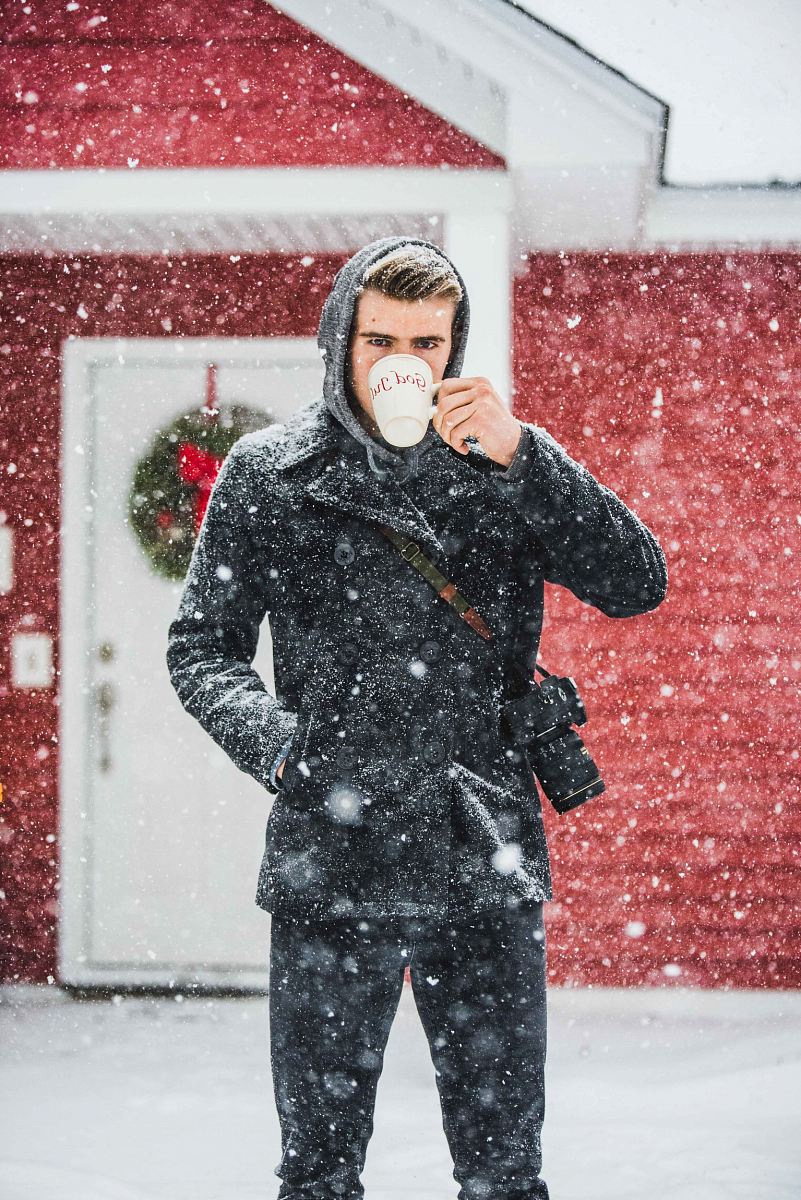 man wearing coat using white mug