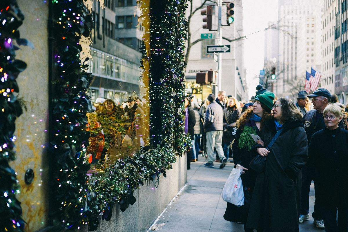 people in sidewalk staring at string lights
