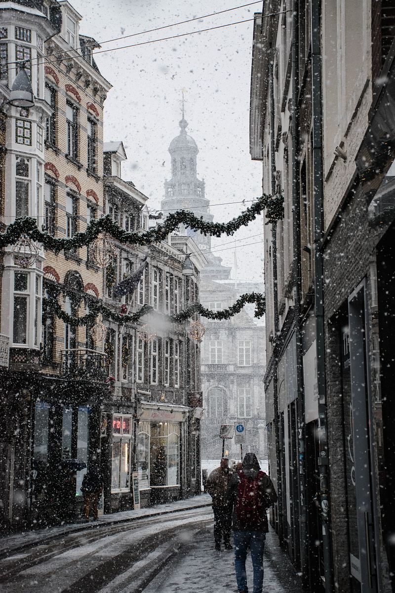 people walking near street between brown building during snow season