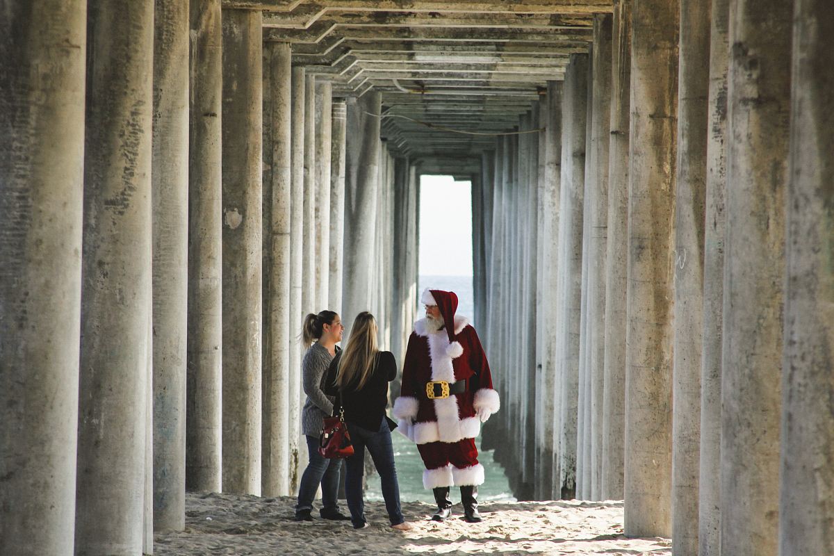 Santa Claus talking to woman near concrete post