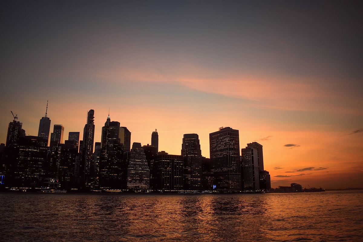 silhouette of high-rise building beside sea during golden hour
