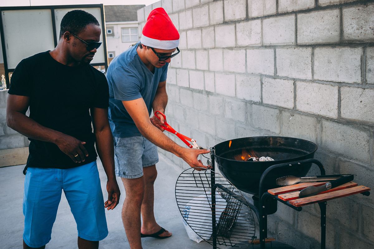 two man standing beside the charcoal grill
