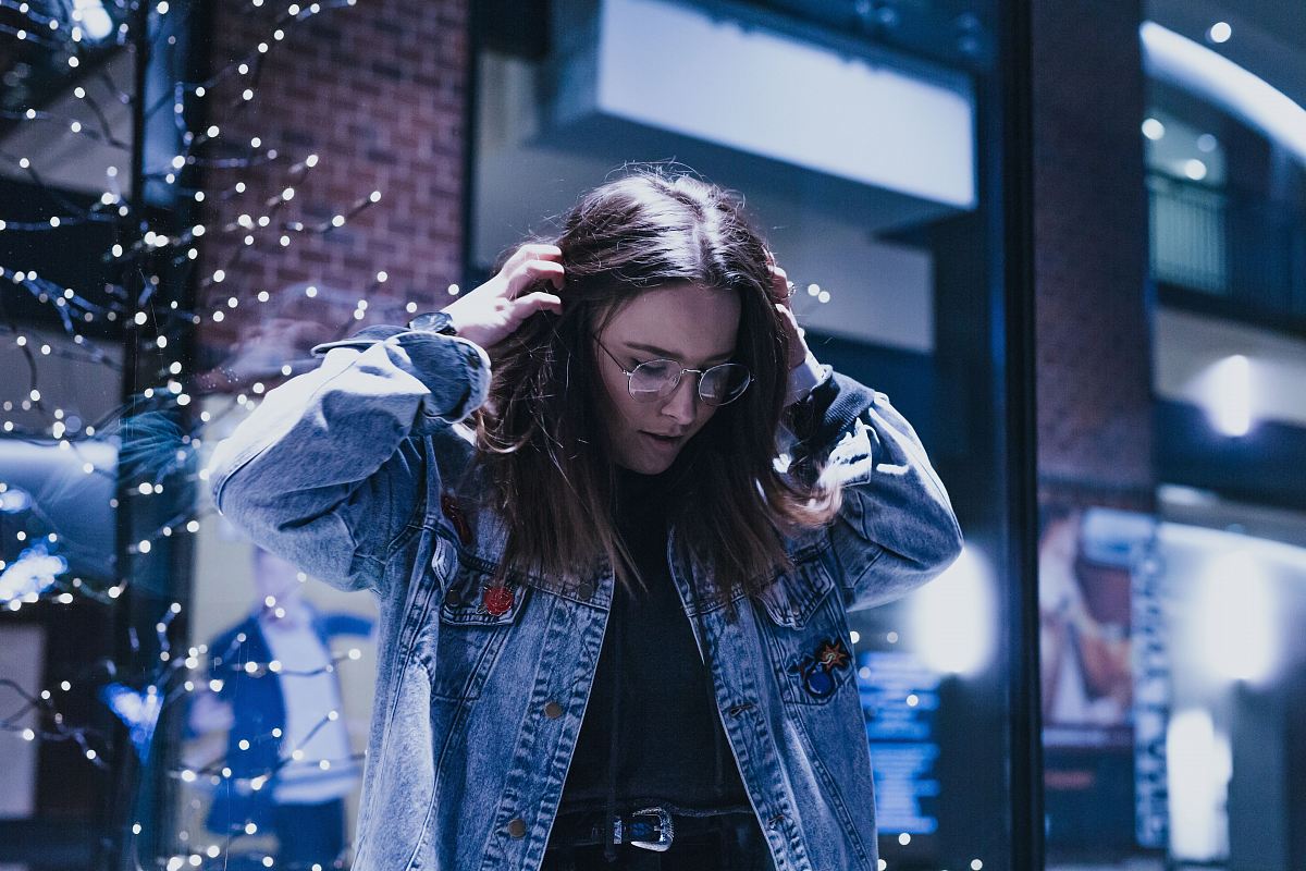 woman fixing her hair near striplights on the wall