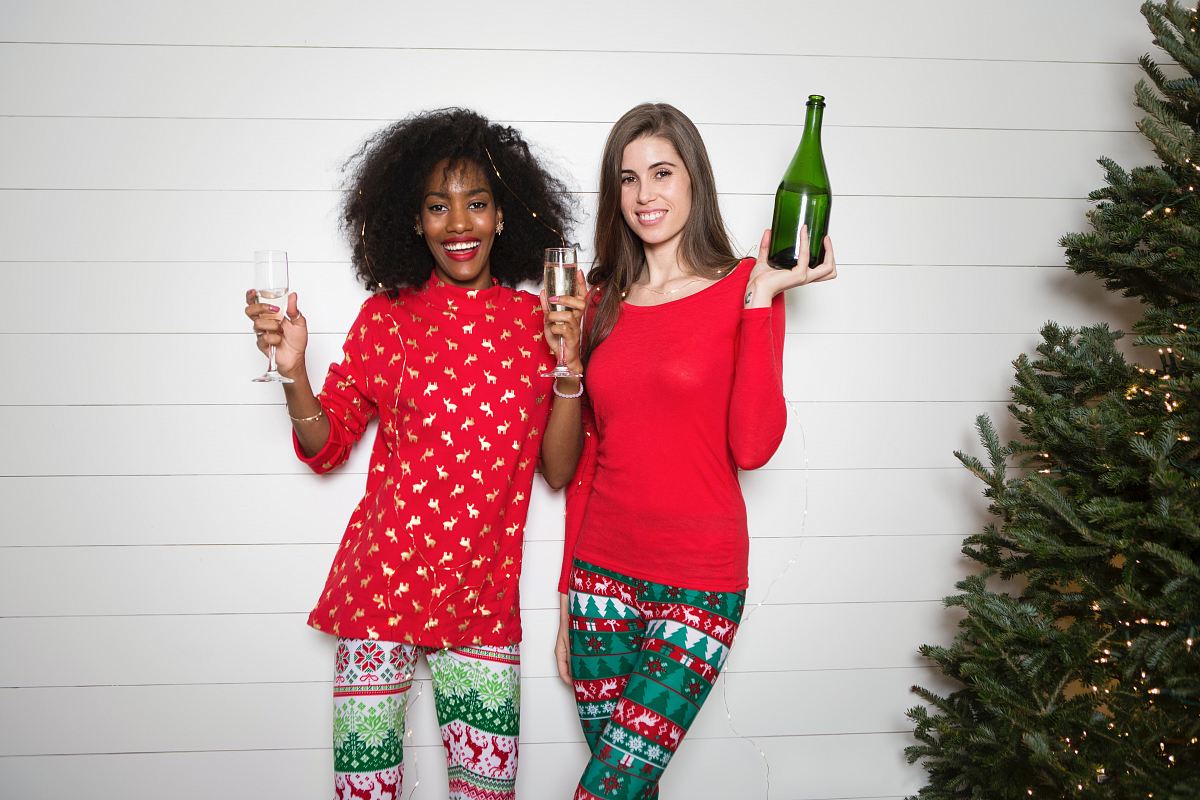 woman holding wine bottle while another woman holding two clear wine glasses