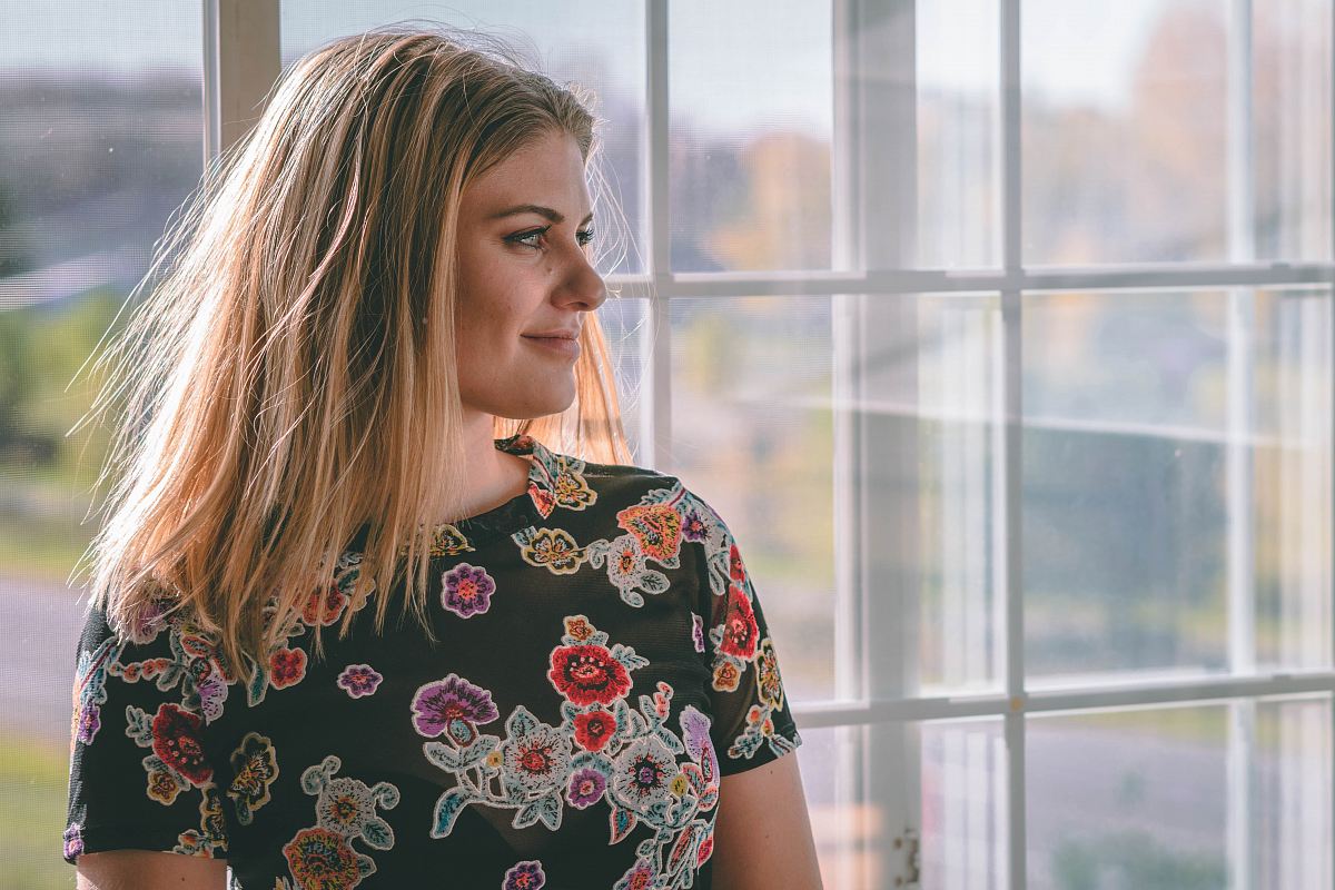 woman wearing black floral dress near the window