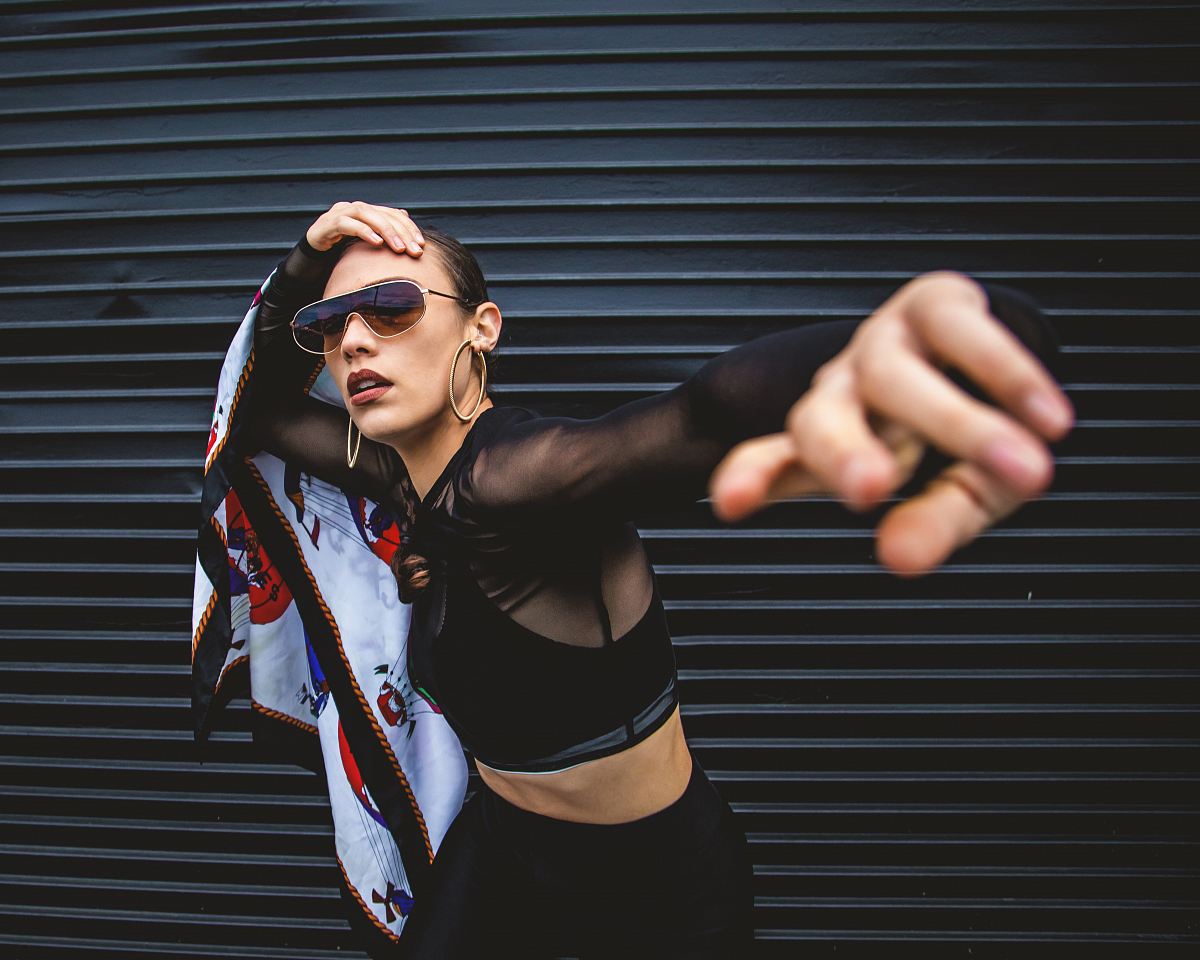 woman wearing black long-sleeved crop top standing beside black roll-up door
