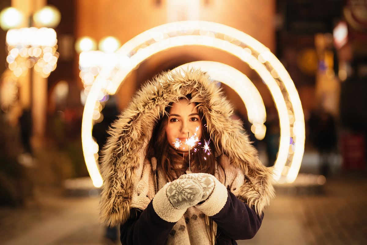 woman wearing coat and holding fireworks